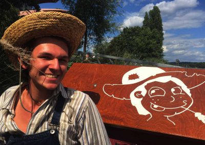 Mann mit Hut neben Huckleberrys Floß